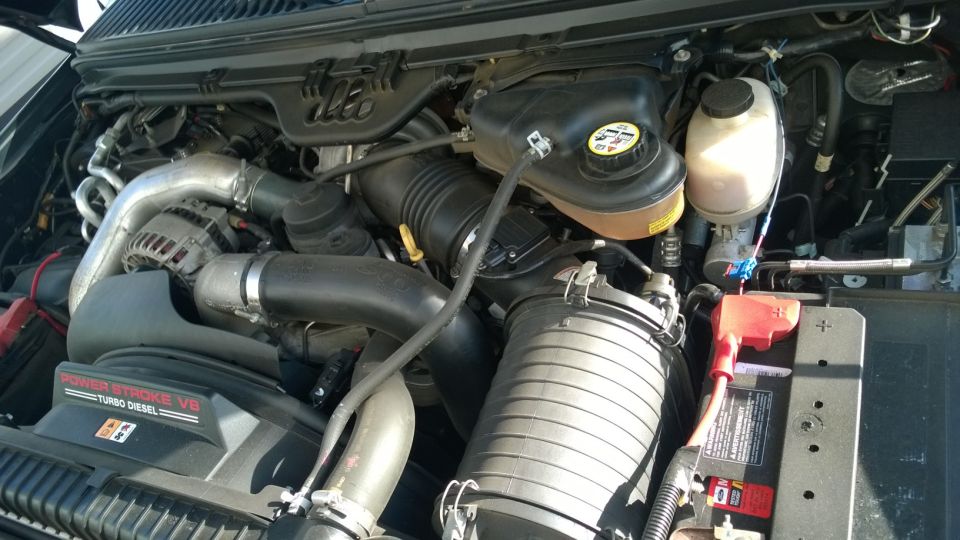 Ford F-250 Power Stroke V8 Turbo Diesel engine bay with air intake, alternator, and battery.