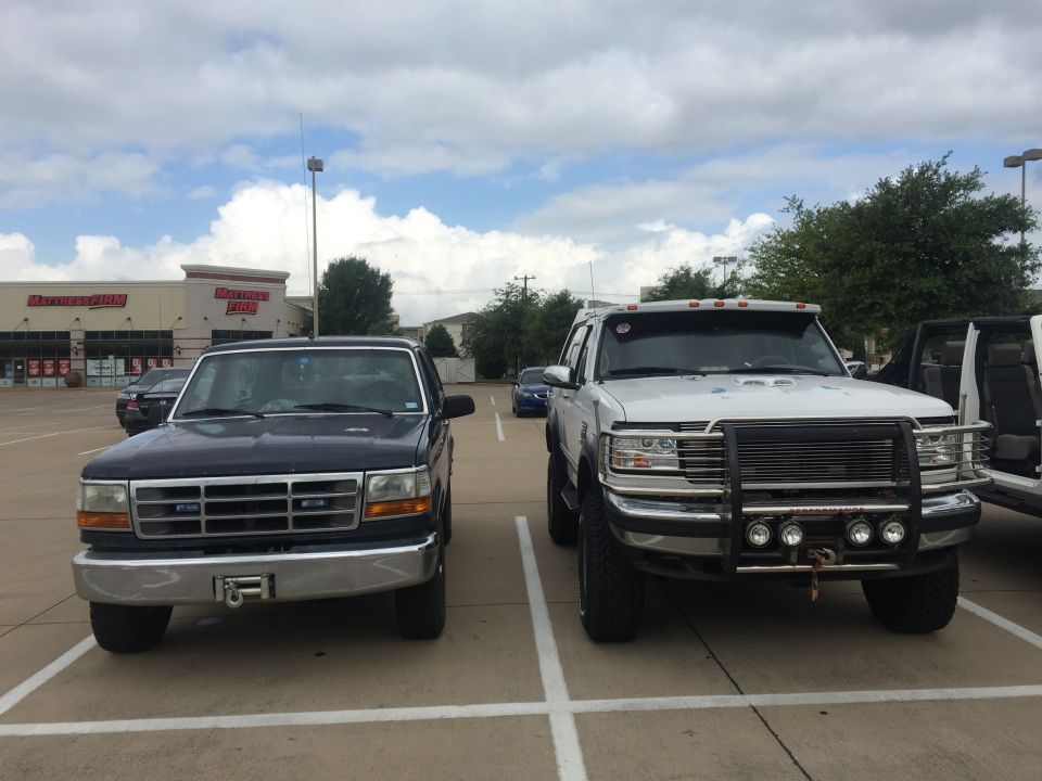 Two pickup trucks parked in a lot, one dark blue, one white.