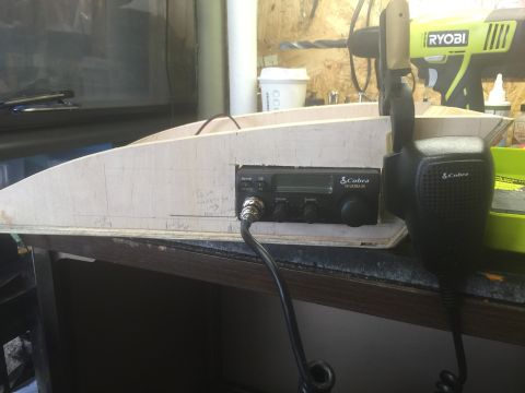 1993 Ford Bronco - A close-up view of a Cobra CB radio and microphone mounted on a wooden structure, likely part of a custom build. The background shows tools…