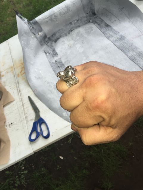 1993 Ford Bronco - A person's hand wearing a ring with a winged animal design is shown in the foreground. In the background, a white table holds a pair of blu…