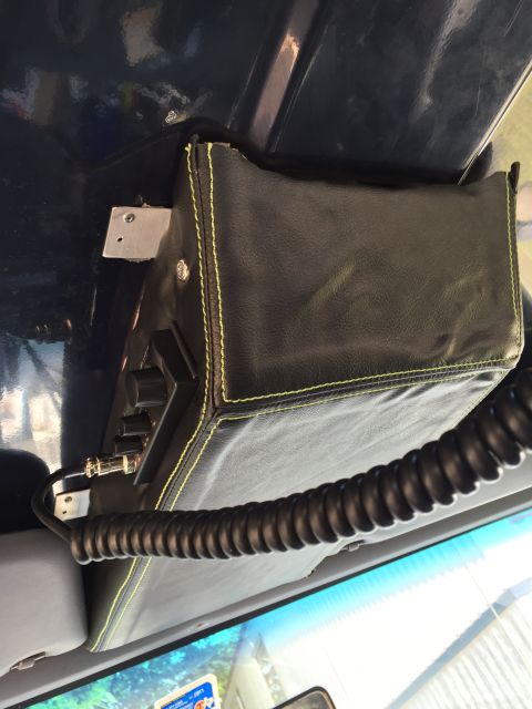 1993 Ford Bronco - A black leather-covered CB radio with yellow stitching is mounted overhead in a vehicle. A coiled microphone cord is attached to the radio.