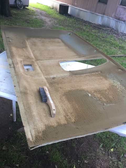 1993 Ford Bronco - A removed car headliner is laid out on a table outdoors, with a wire brush resting on it. The headliner appears to be dirty and in the proc…