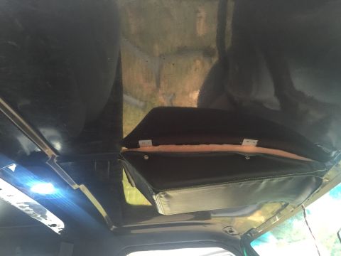 1993 Ford Bronco - The interior of a vehicle shows a custom black headliner with a padded overhead storage compartment. A bright blue LED light is visible on…