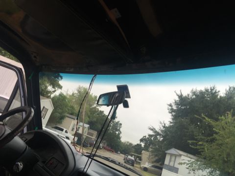1993 Ford Bronco - Interior view of a vehicle looking out the windshield. Wires are hanging down from the headliner near the rearview mirror.