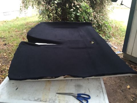 1993 Ford Bronco - Two black upholstered car door panels or headliner pieces are laid out on a white table outdoors. A pair of blue-handled scissors rests on…