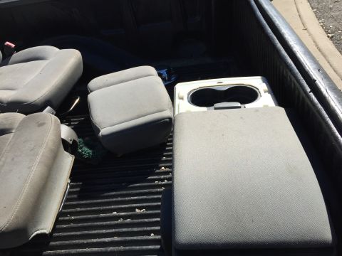 1993 Ford Bronco - Two front bucket seats and a center console with cup holders are loaded in the bed of a pickup truck.