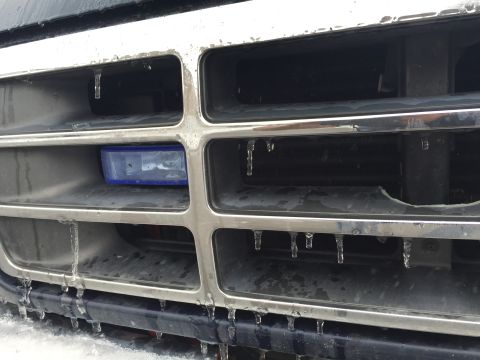 1993 Ford Bronco - A close-up view of a vehicle's chrome grille with icicles hanging from it. A blue fog light is visible in the lower grille opening.