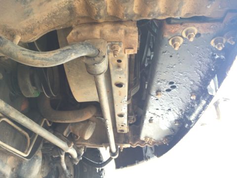 1993 Ford Bronco - The underside of a vehicle shows a sway bar and suspension components, with a black painted frame and various rusty metal parts.