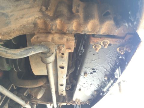 1993 Ford Bronco - Underside view of a vehicle's suspension system, showing a sway bar, mounting brackets, and frame components. The parts appear to be heavil…