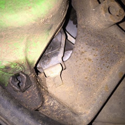 1993 Ford Bronco - A close-up view of a heavily soiled mechanical component, possibly part of a braking system or suspension, showing rust and dirt accumulati…