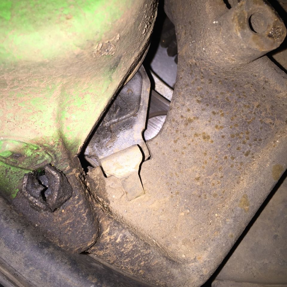 Close-up of dirty and rusty vehicle part with green painted surface.