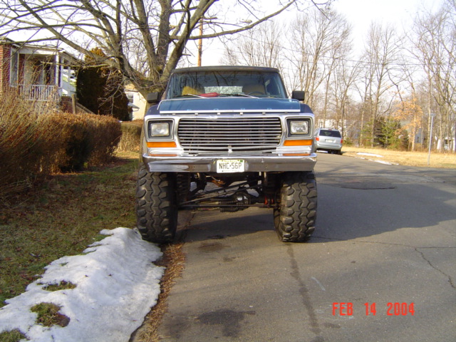 Lifted blue pickup truck front view with large tires and chrome grille