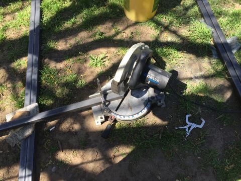 1993 Ford Bronco - A chop saw is set up on the ground next to several pieces of metal stock. A yellow bucket is visible in the background.
