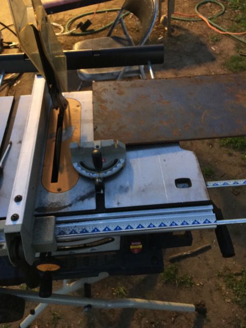 1993 Ford Bronco - A table saw is set up outdoors with a piece of metal on its surface. A chair and garden hoses are visible in the background.