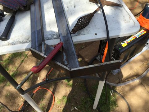 1993 Ford Bronco - A metal frame is being welded on a table with various tools including a clamp, hammer, and welding machine visible. The scene appears to be…