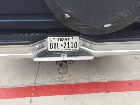 1993 Ford Bronco - The rear of a dark blue vehicle shows a Texas license plate reading DDL-2110. A spare tire cover is visible above the license plate.