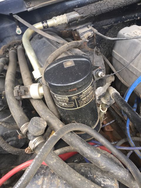 1993 Ford Bronco - A close-up view of the engine bay of a 1993 Ford Bronco, focusing on the air conditioning system components and various hoses and wiring.