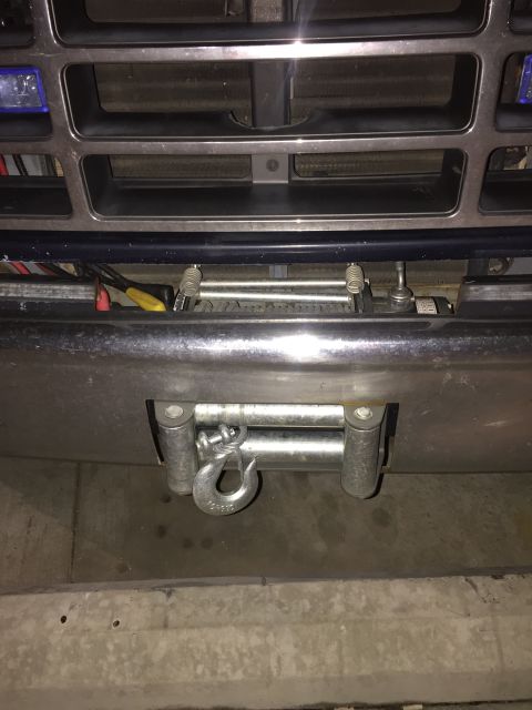 1993 Ford Bronco - A heavy-duty winch with a steel cable and hook is mounted to the front bumper of a vehicle. The winch is positioned below the vehicle's gri…