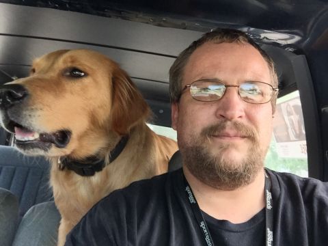 1993 Ford Bronco - A man and his golden retriever dog are in the interior of a vehicle. The man is wearing glasses and a black t-shirt with lanyards around hi…