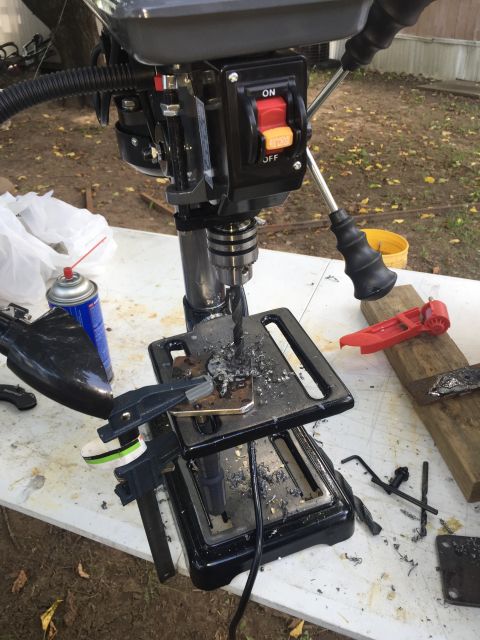 1993 Ford Bronco - A drill press is set up outdoors on a table, with metal shavings scattered around the work area. Various tools, including clamps, drill bit…