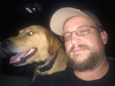 1993 Ford Bronco - A man wearing glasses and a baseball cap takes a selfie with a golden retriever in a car at night.