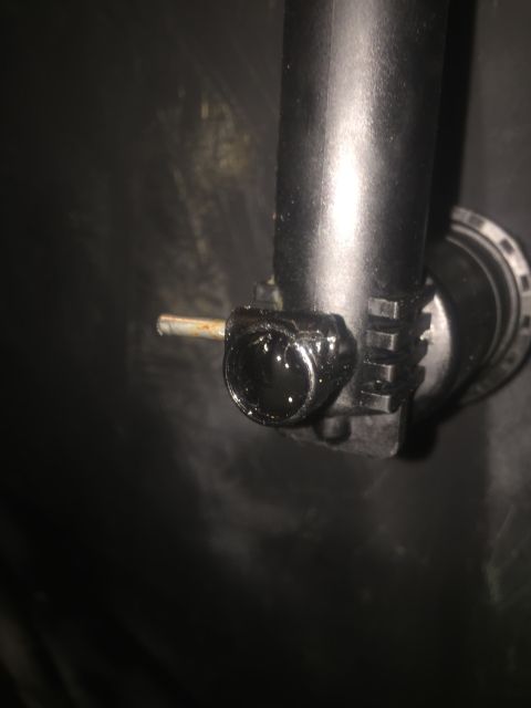 1993 Ford Bronco - A close-up view shows a black plastic pipe with a metallic component attached, exhibiting some signs of wear and liquid residue. The backgr…