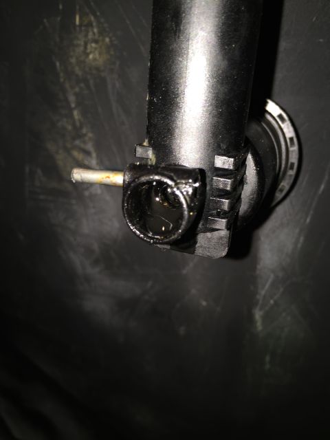 1993 Ford Bronco - A close-up view of a black plastic component, possibly part of a fluid reservoir or pump, with a metal tube protruding from its side. The c…
