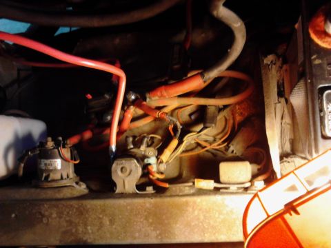 1973 Ford F-250 - A close-up view of a vehicle's engine bay, focusing on red battery cables and electrical components. Several relays and wiring harnesses ar…