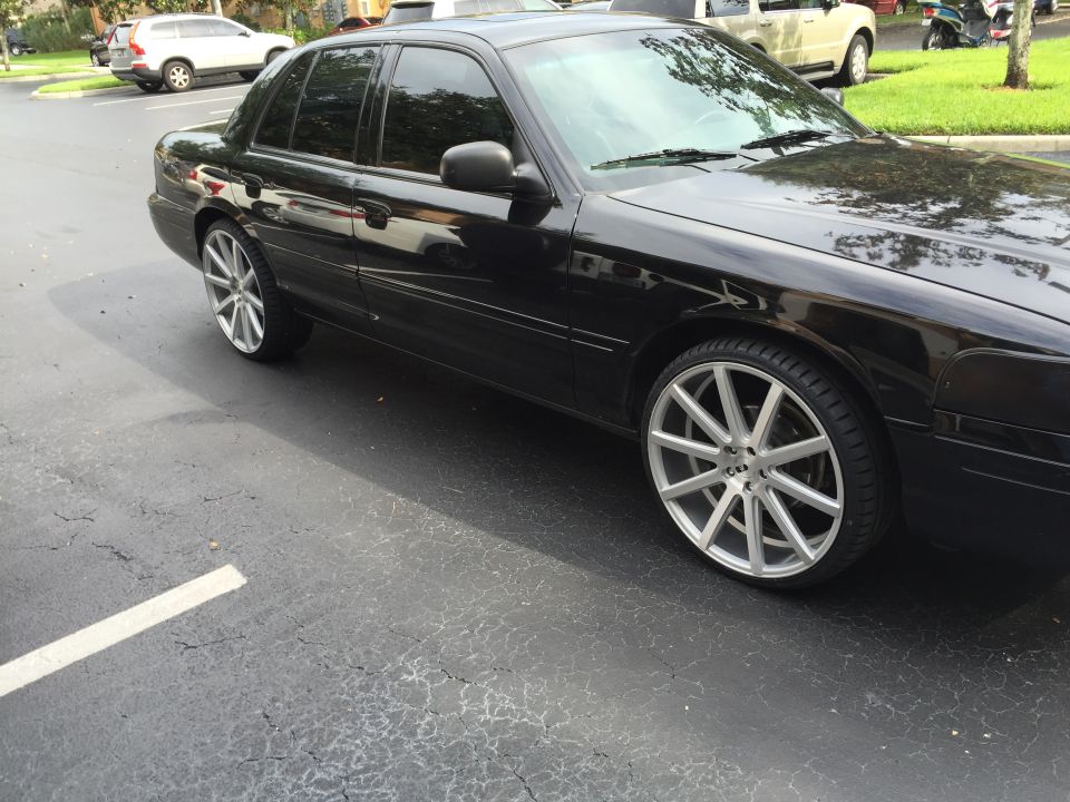 Black Ford Crown Victoria with custom silver wheels, side view.