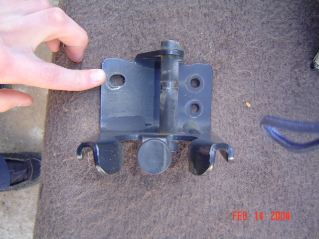 Spare tire rack bracket with a hand pointing to a hole
