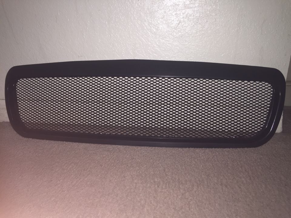 Black mesh grille with black frame on carpet.