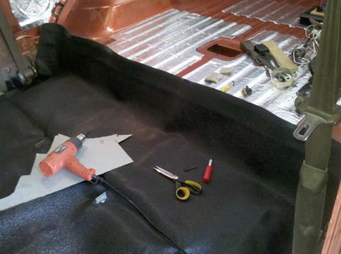 1982 Ford Bronco - The interior of a vehicle is being worked on, with sound deadening material laid out on the floor and a heat gun and scissors nearby. The v…