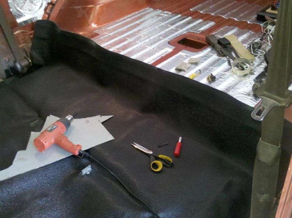 Interior of a Ford Bronco being soundproofed with heat gun and tools on the floor.