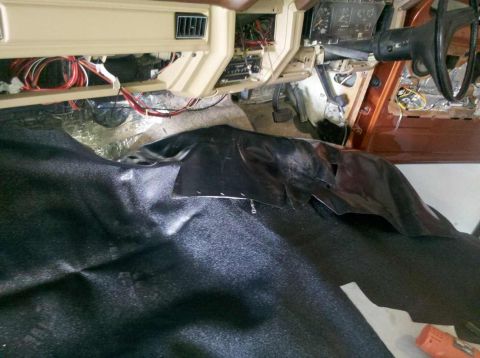 1982 Ford Bronco - The interior of a vehicle is shown with the dashboard and steering wheel visible. Black carpeting and sound deadening material are laid out…