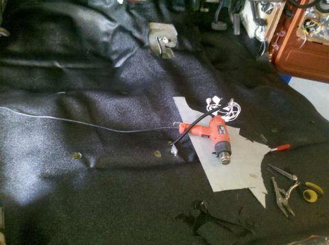 1982 Ford Bronco - The interior of a vehicle is shown with black carpeting and a heat gun resting on a piece of paper. Various wires and tools are also visibl…