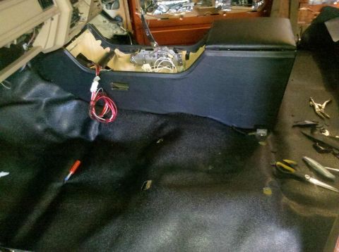 1982 Ford Bronco - The interior of a vehicle is shown with the center console and floor carpet partially installed. Wires and tools are visible on the floor a…