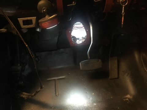 1978 Ford Bronco - The interior of a vehicle's footwell shows the clutch, brake, and gas pedals. A hole in the firewall is visible above the pedals, revealing…
