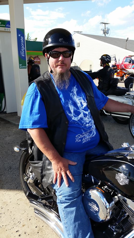 Man on a black Harley-Davidson motorcycle with chrome accents.