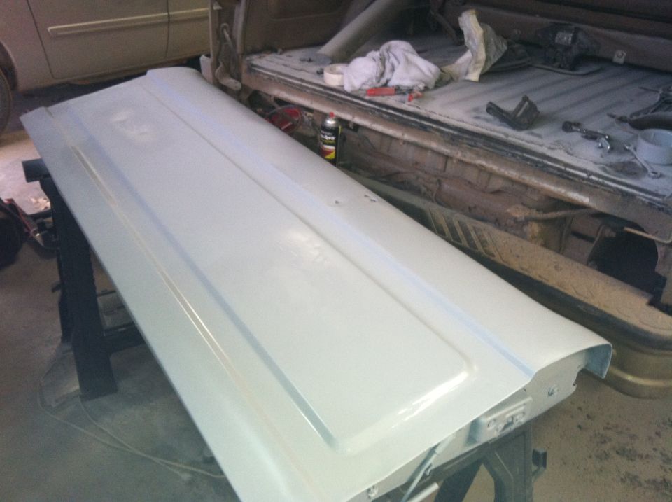 Light gray painted tailgate in front of a pickup truck bed with tools.