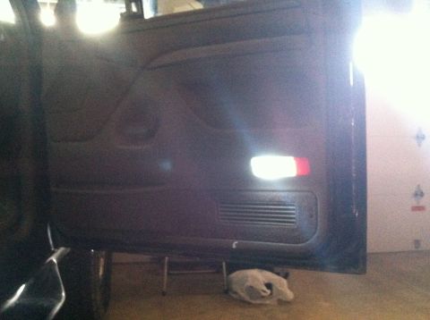 2004 Ford F-250 - The interior door panel of a vehicle is shown with a bright LED light installed near the door handle. A speaker grille is visible below the…