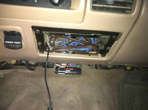 2004 Ford F-250 - The interior of a vehicle's dashboard shows a removed radio or storage compartment filled with tangled brown and blue wires. Below the comp…
