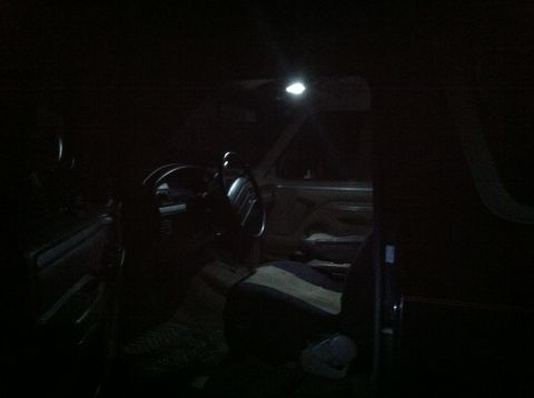 2004 Ford F-250 - The interior of a dark vehicle is illuminated by a small overhead light. The steering wheel, dashboard, and a portion of the driver's seat…