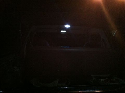 2004 Ford F-250 - Interior view of a dark vehicle at night, with three small LED dome lights illuminated on the ceiling. The rear window is visible, showing…