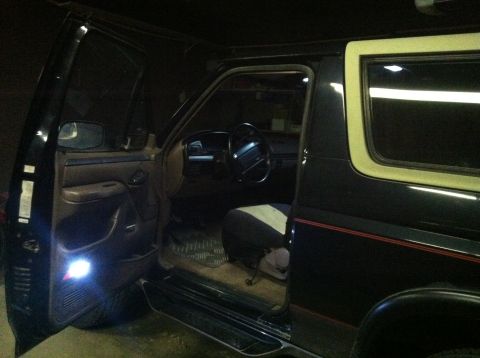 2004 Ford F-250 - The interior of a dark-colored SUV is shown with the driver's side door open. The steering wheel, dashboard, and part of the driver's seat…