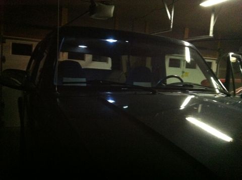 2004 Ford F-250 - The front interior of a dark-colored pickup truck is visible, illuminated by overhead lights. The windshield and dashboard are prominent, w…