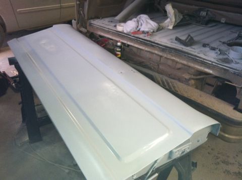 2004 Ford F-250 - A primed white tailgate is laid across two sawhorses in front of the bed of a pickup truck. The truck bed contains various tools and suppli…
