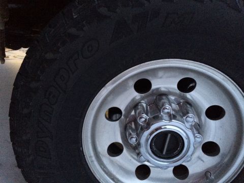 2004 Ford F-250 - A close-up view of a shiny chrome hubcap and a black tire on a Ford F-250. The tire has "Dynapro ATm" text visible.