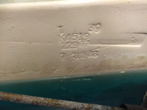 2004 Ford F-250 - Embossed text and numbers are visible on the underside of a cream-colored vehicle part, possibly a fender or body panel, above a turquoise…