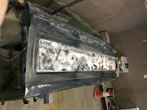 2004 Ford F-250 - A close-up, overhead view of a dark-colored truck tailgate that has been prepped for bodywork. The tailgate has a large section of body fil…