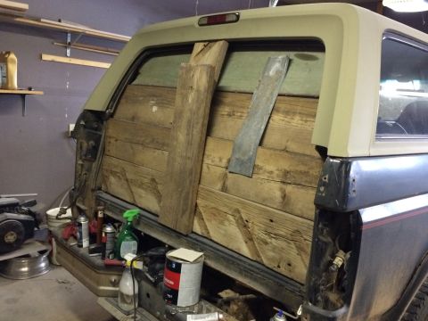 2004 Ford F-250 - The rear of a dark blue SUV with a custom wooden paneling in the cargo area is shown in a garage setting. Various tools and cleaning suppli…
